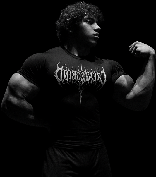 Person wearing a black t-shirt with 'CREATEKIND' logo, flexing muscles on a dark background